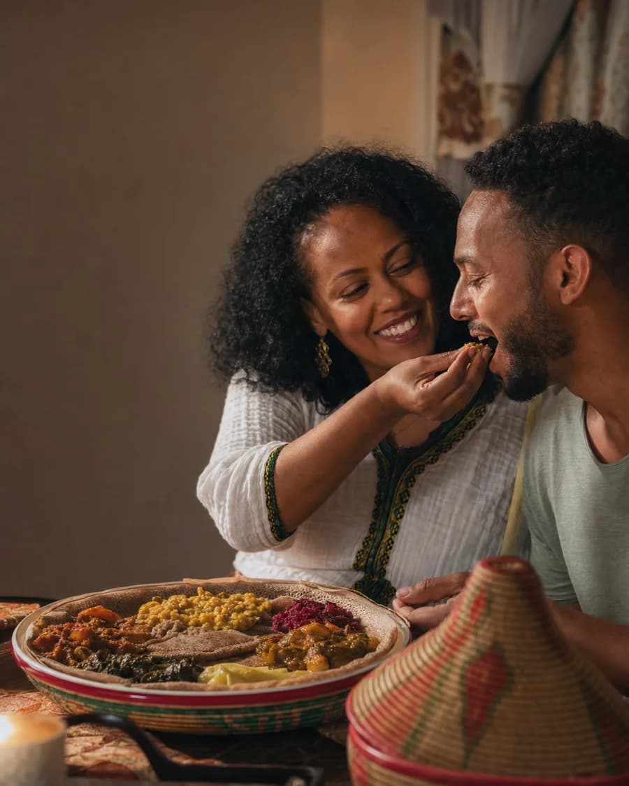 An Ethiopian woman offering a gursha bite to a loved one at home